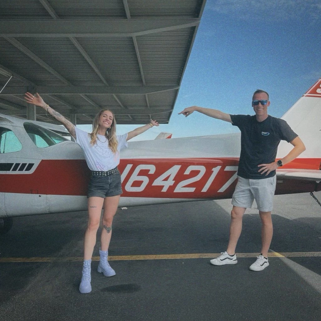 Flight instructor and a new pilot celebrating beside a Cessna 172 after a checkride