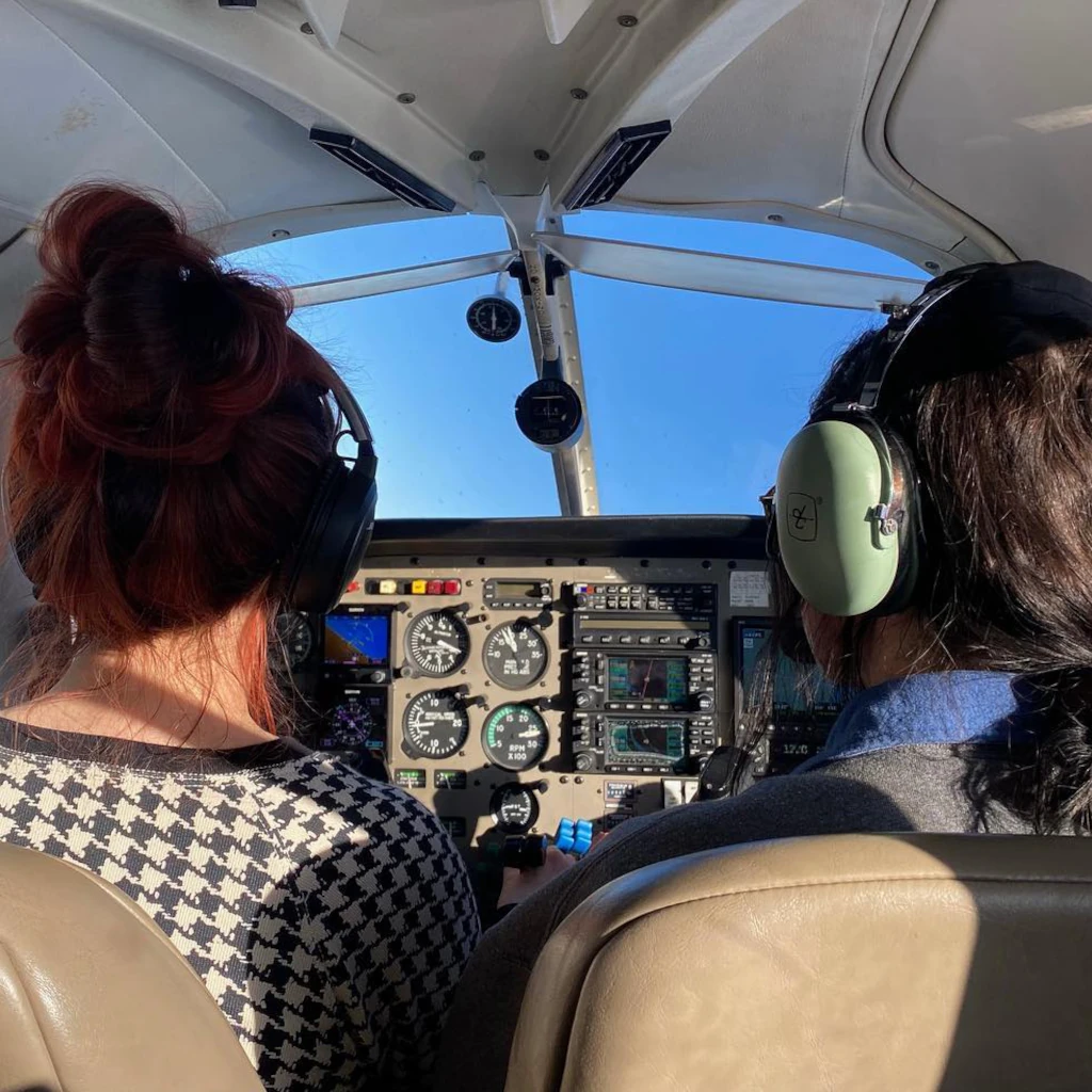 Two pilots with headsets in cockpit seen from behind
