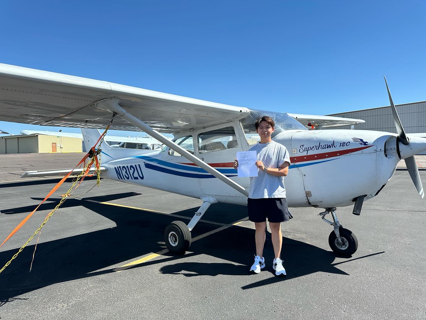 Student holding certificate in front of a Cessna 172 airplane